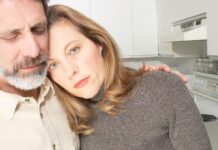 Qué hacer cuando descubres que no te casaste con quien creías Pareja abrazada en una cocina, con expresión seria y cercana, transmitiendo apoyo mutuo en un momento difícil de la vida en pareja.