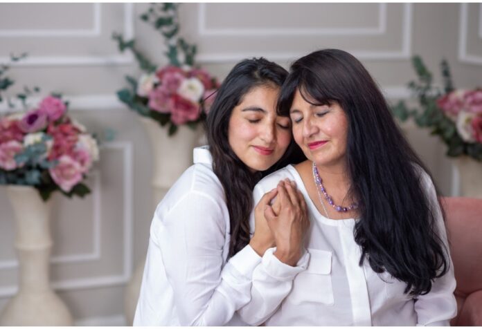 Madre e hija adultas abrazadas en un ambiente cálido, mostrando cercanía, afecto y confianza emocional.