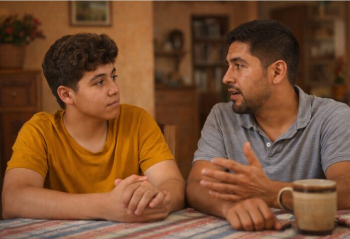 Padre conversa seriamente con su hijo adolescente en casa, en un ambiente cálido y cercano.