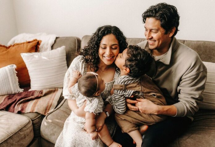 Padres con sus dos hijos pequeños compartiendo un momento de afecto y cercanía en casa.